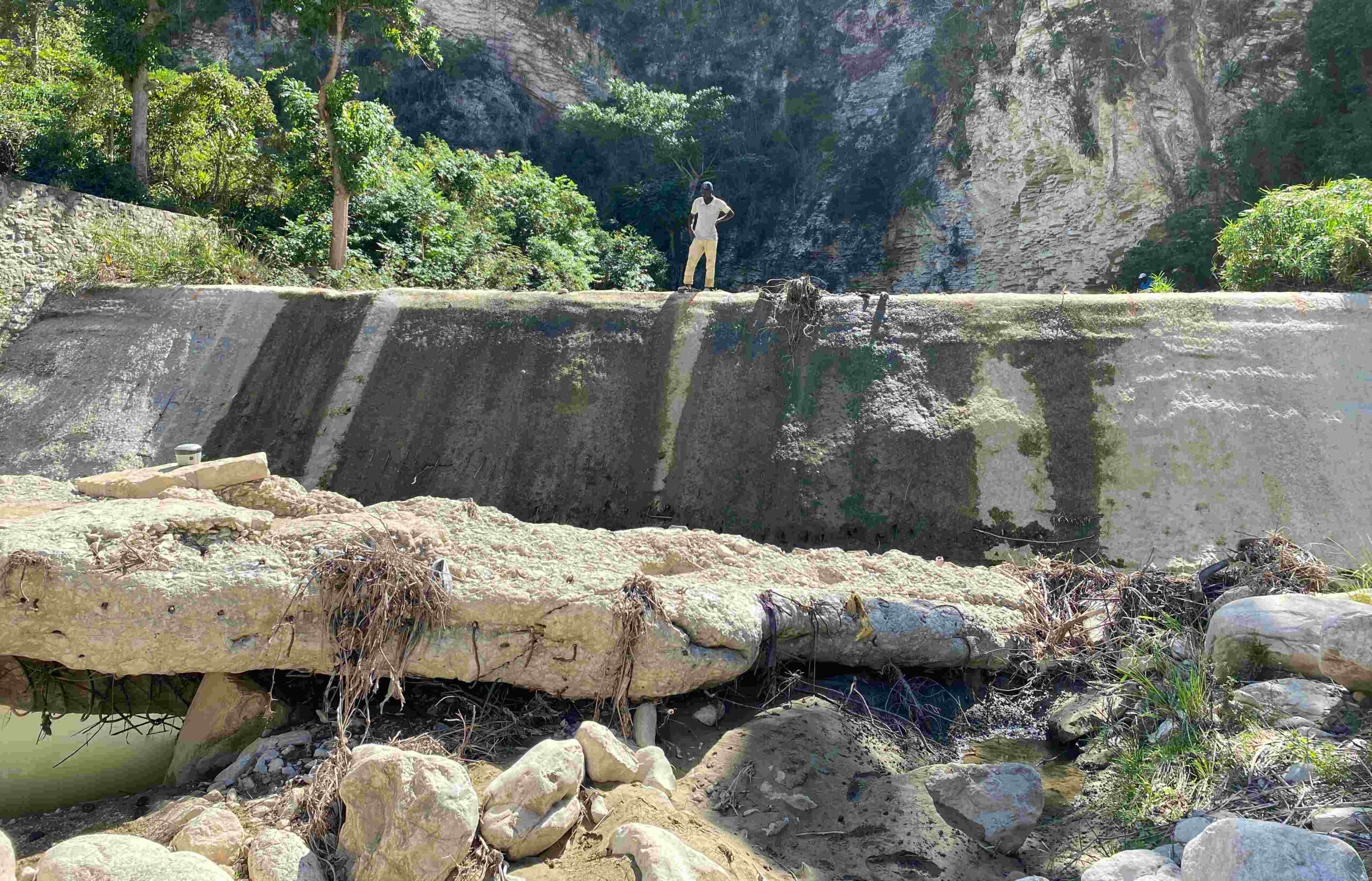 An unidentifiable person stands at the top of a dam's spillway
